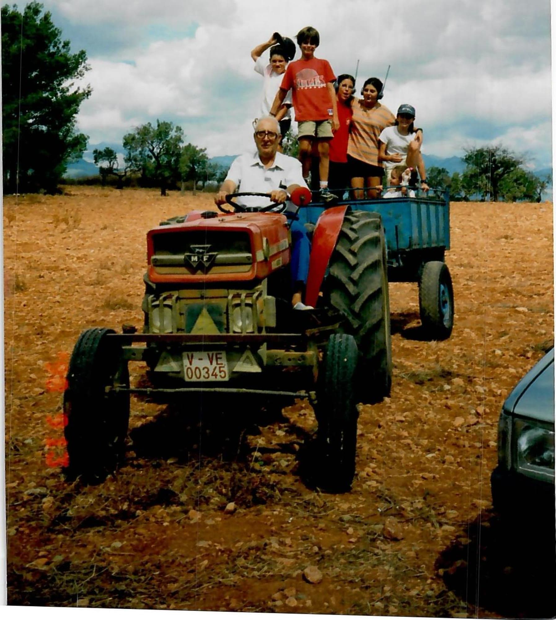 Grandfather driving the tractor with the grandchildren riding the trailer